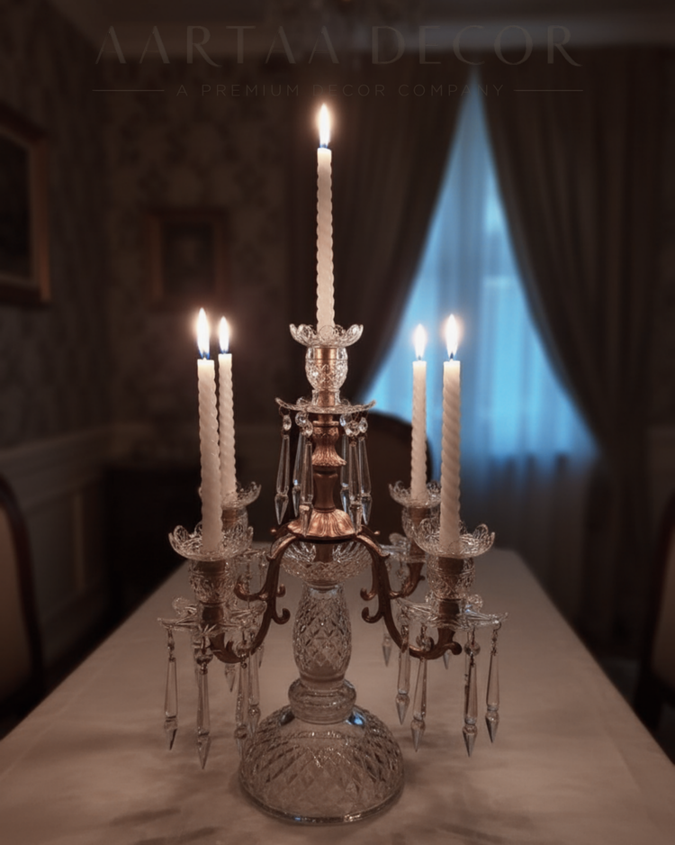 Decorative crystal candelabra with lit candles on a table in a dimly lit room.