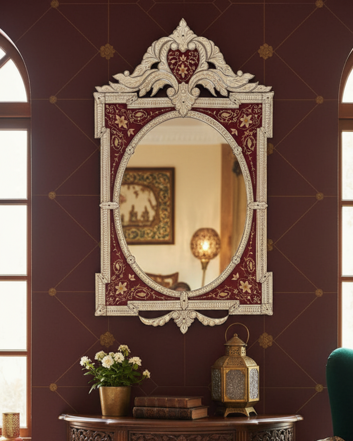 Decorative mirror with intricate design on a wall with floral arrangement and lantern.