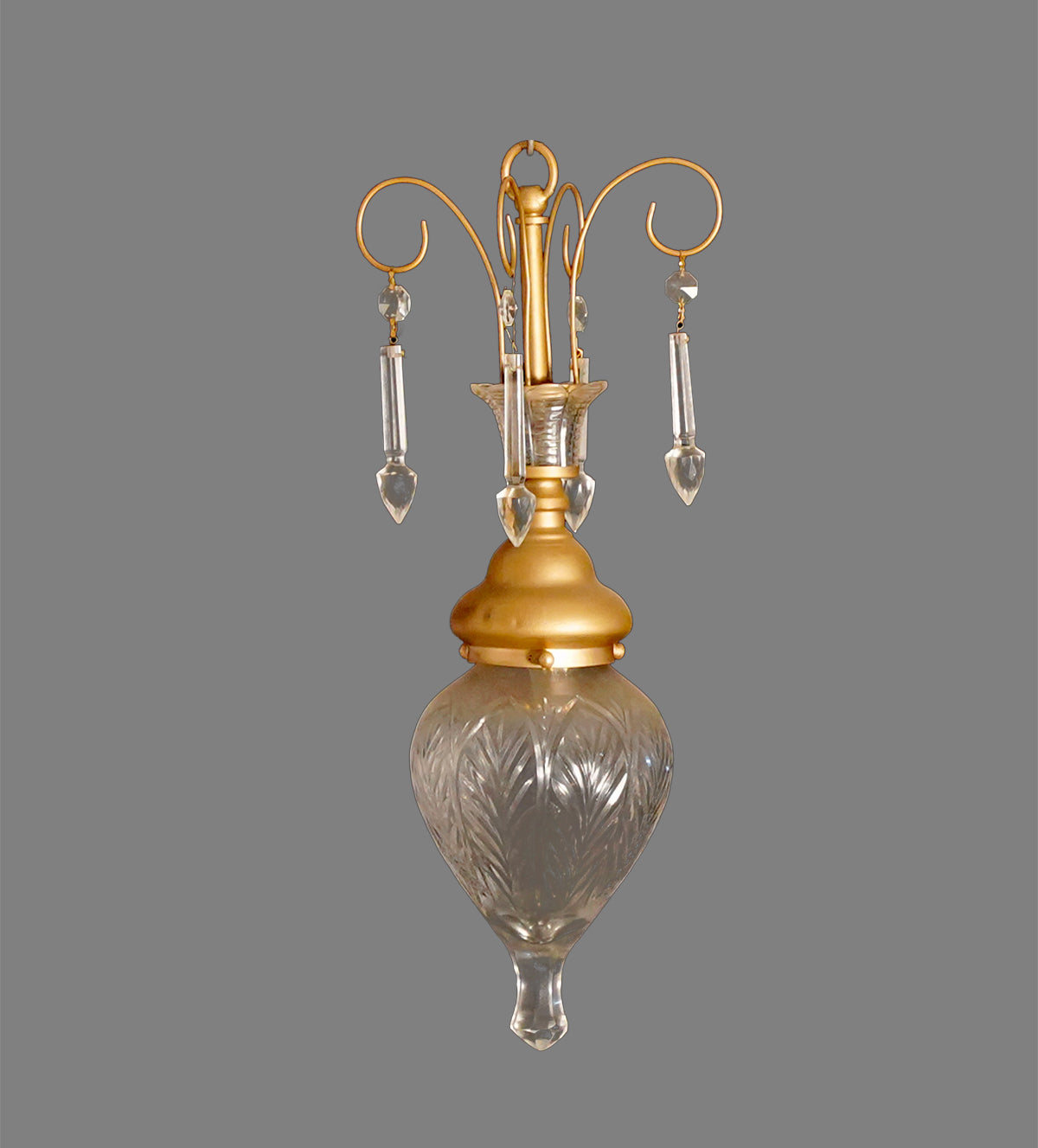 Elegant gold and glass teardrop pendant lights with crystal accents, hanging in a stylish room with yellow walls and a cozy yellow armchair.