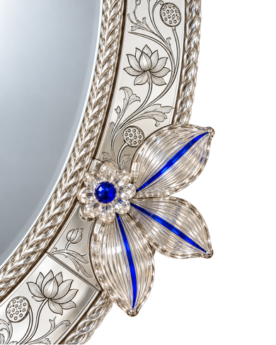 Close-up of an ornate silver mirror frame featuring a floral design with a blue gemstone center and a flower motif made of clear rhinestones and blue enamel.
