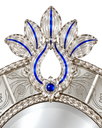 Close-up of an ornate silver-toned decorative frame or mirror border with sculpted floral and leaf motifs, bright blue inlay accents, and a central blue gemstone on a white background.