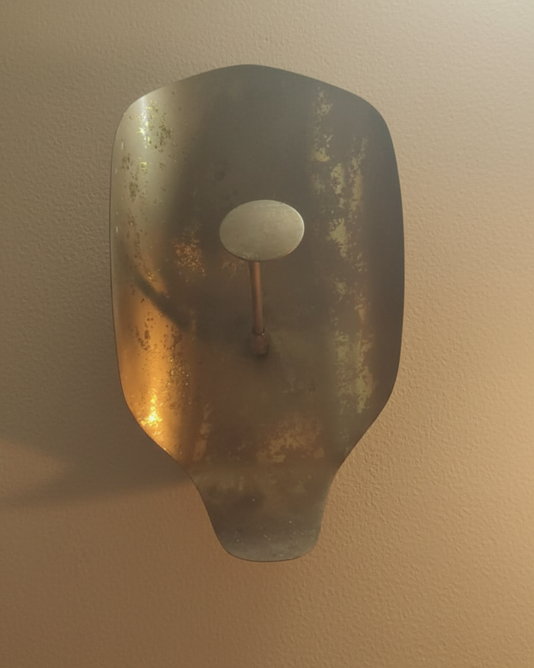 Decorative wall sconce with a metallic finish on a beige wall.