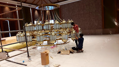 Team assembling a brass and glass chandelier on site