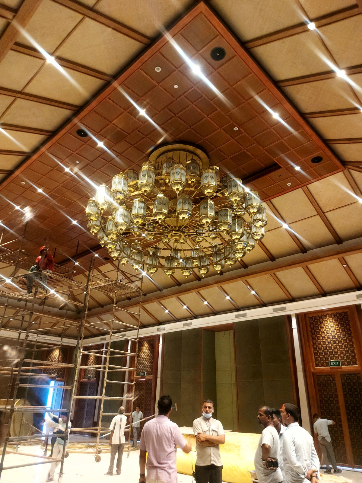 Brass and glass chandelier suspended in an interior during installation